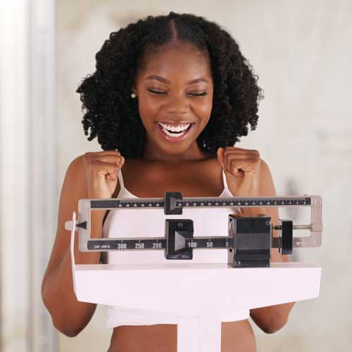 Smiling woman celebrating her weight loss success on a scale