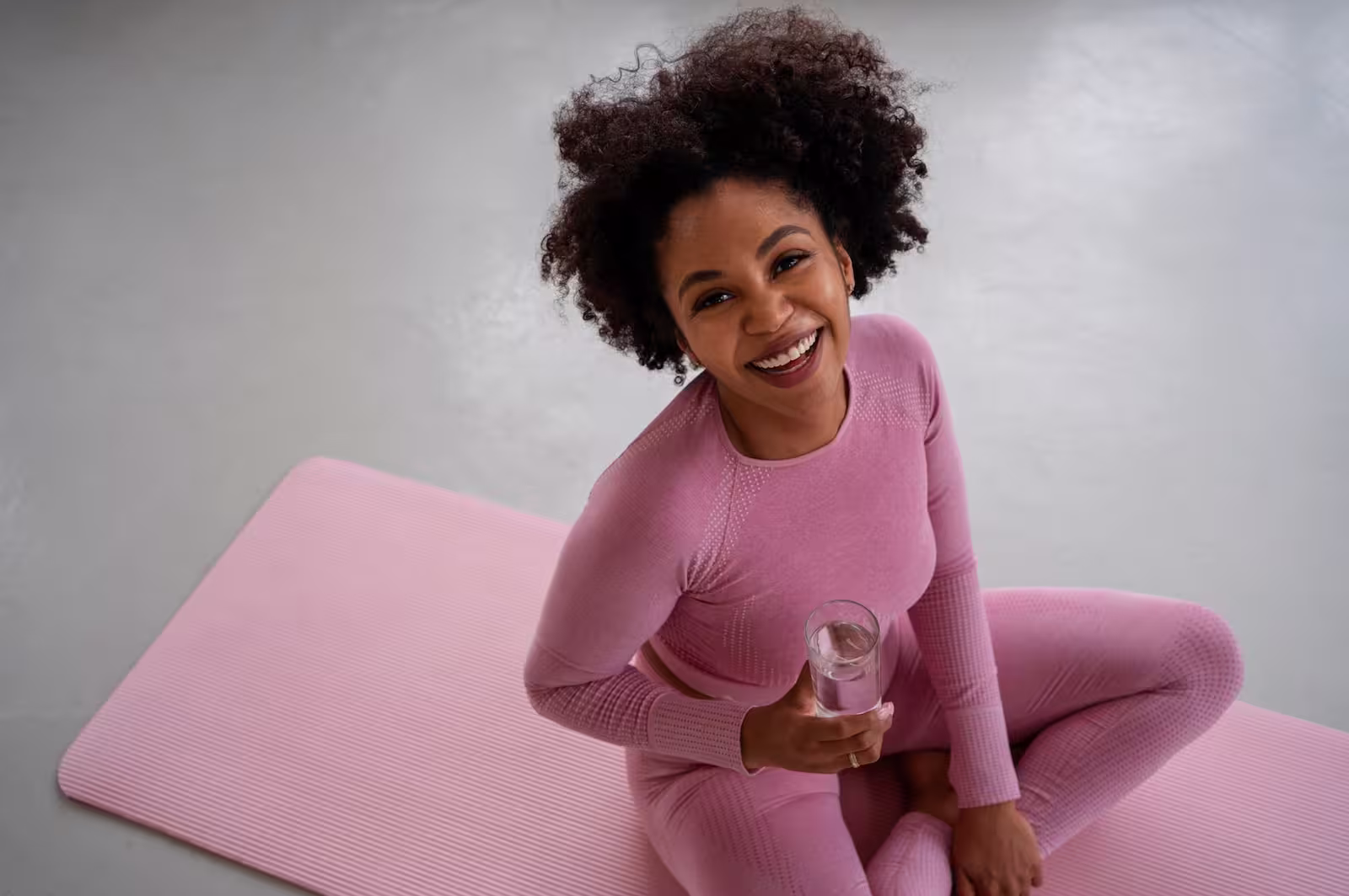 Woman sitting on a yoga mat in pink activewear